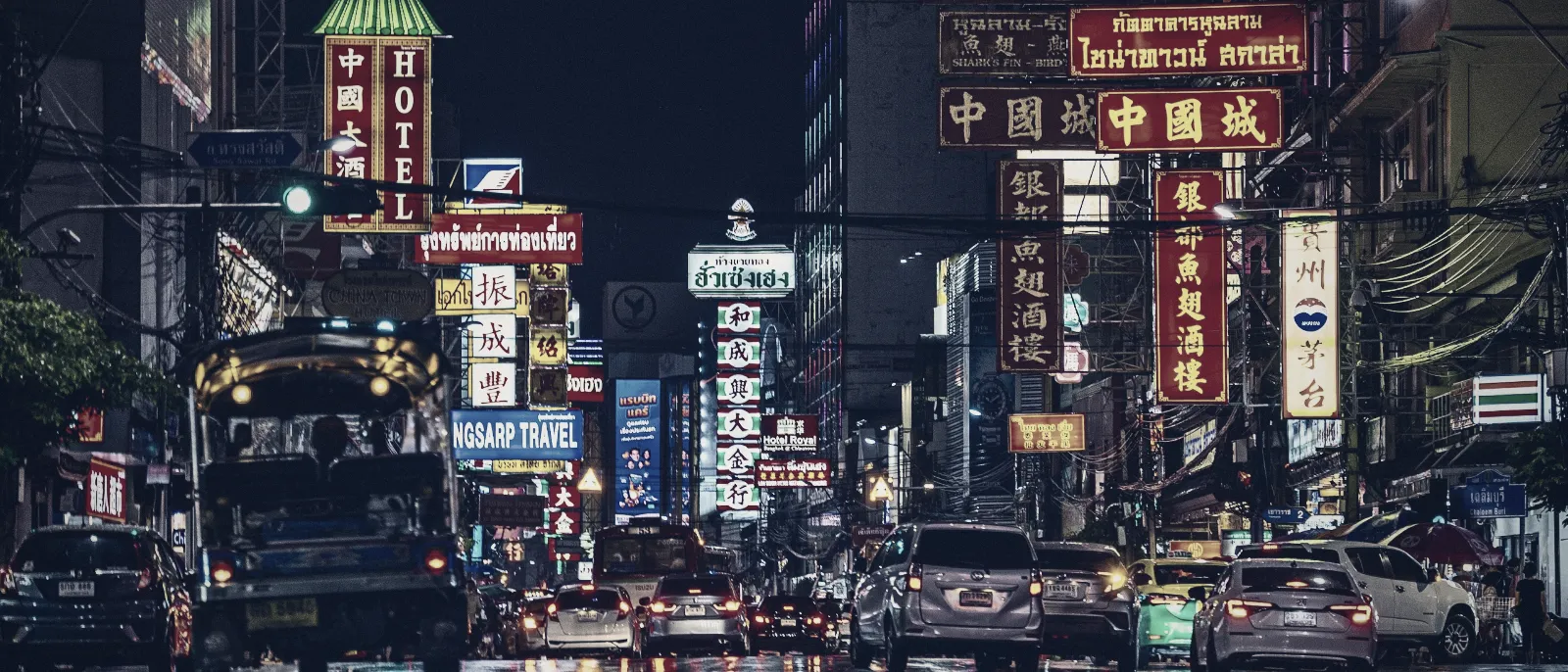 A busy Bangkok street at night lit by neon signs