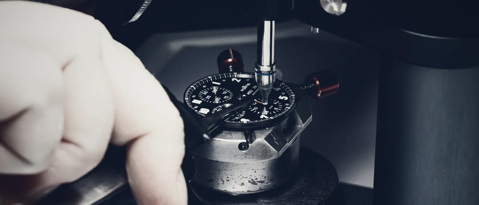 Hands working on a wristwatch movement during an inspection