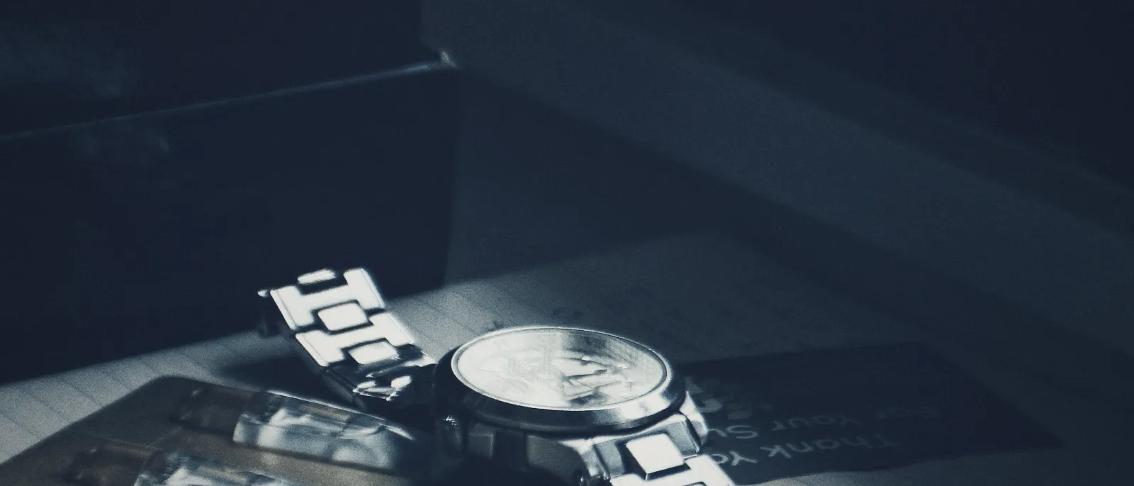 A wristwatch resting on papers beside a window
