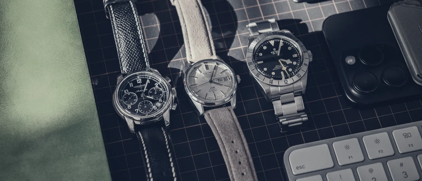 Three wristwatches laid out on a desk for comparison