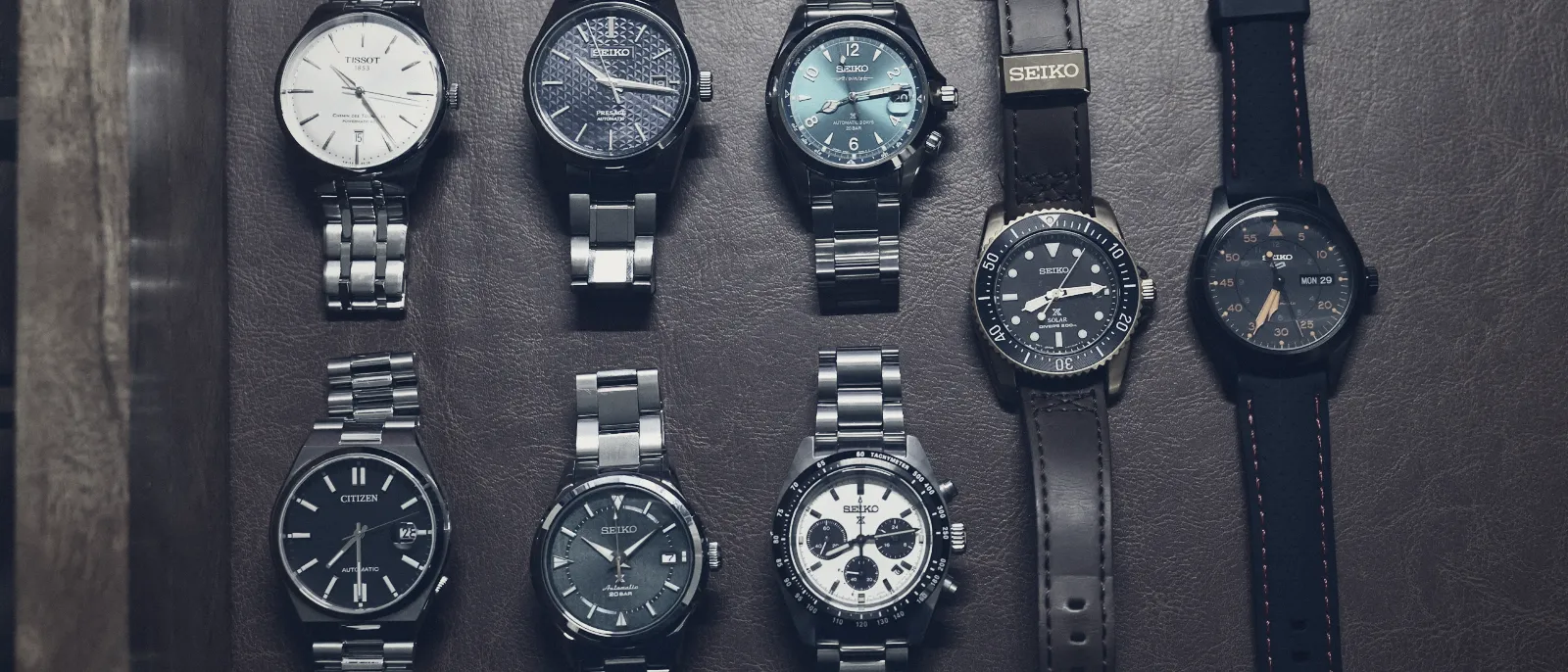 A collection of wristwatches laid out on a brown surface
