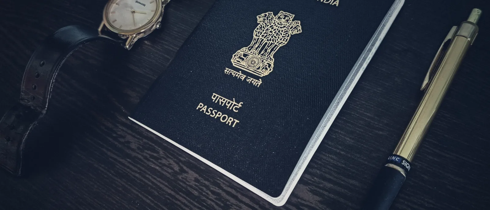 A passport, a wristwatch and a pen on a table